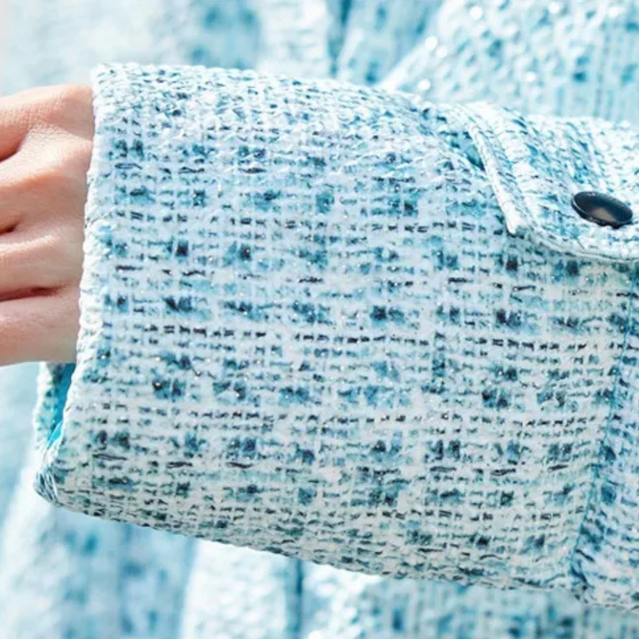 Blauwe tweed jas met knoopdetail, close-up van mouwtextuur. Modieuze dameskleding, herfst-winter collectie, hoogwaardige stof.