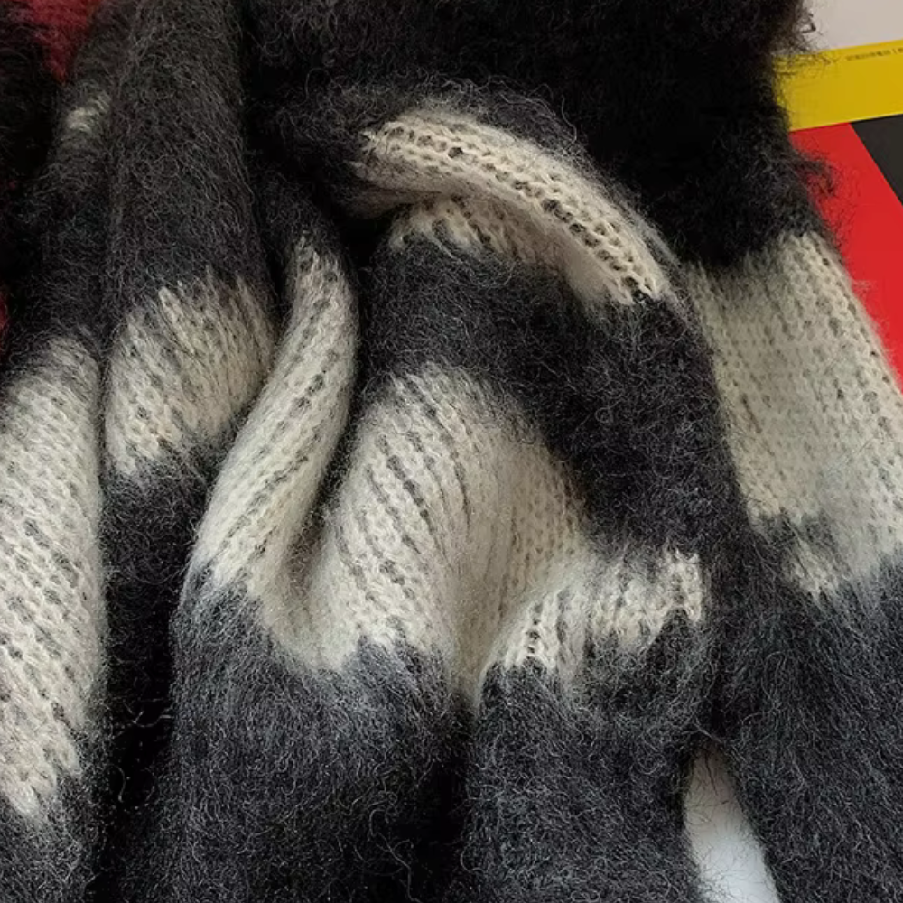 Zachte, gebreide sjaal met zwart-wit gestreept patroon, gemaakt van pluizige wol. Perfect voor wintermode en warme accessoires.