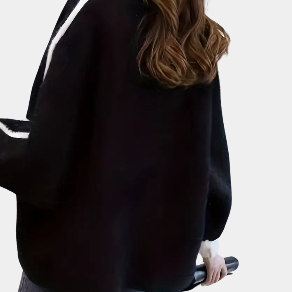 Vrouw in zwarte trui met witte strepen, bruine golvende haren, houdt een zwarte paraplu vast. Modieuze herfstkleding, casual stijl.