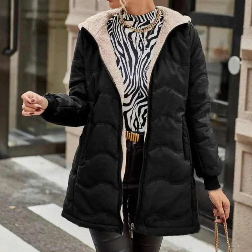 Vrouw in zwarte gewatteerde jas met capuchon en zebraprint trui, modieuze winterkleding, stedelijke achtergrond, trendy damesmode.