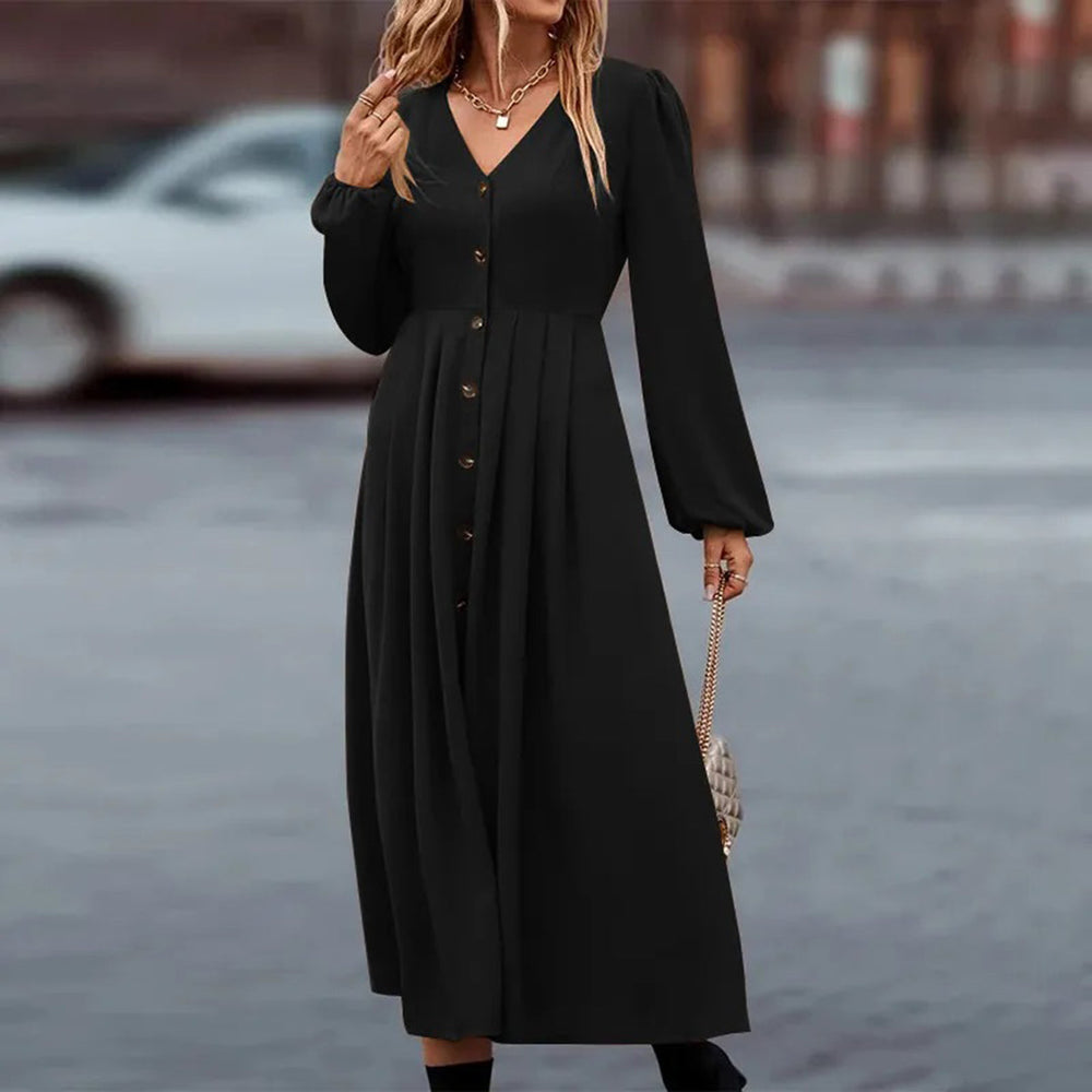Zwarte lange jurk met knoopsluiting en pofmouwen, gedragen door een vrouw. Stijlvolle damesmode, perfect voor herfst- en winterseizoen.