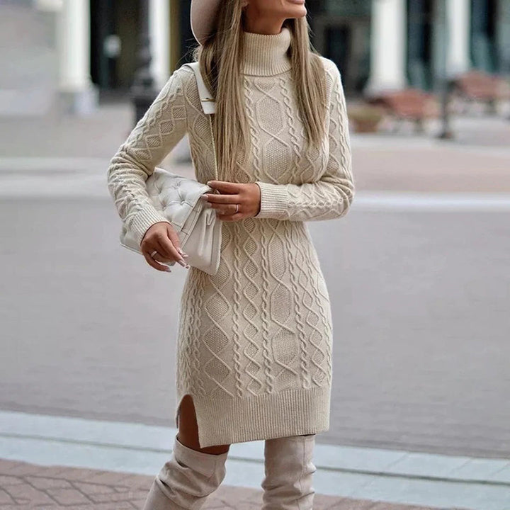 Dames lange gebreide coltrui jurk in beige, stijlvolle herfstmode, gecombineerd met een witte handtas en hoge laarzen, ideaal voor casual chic look.