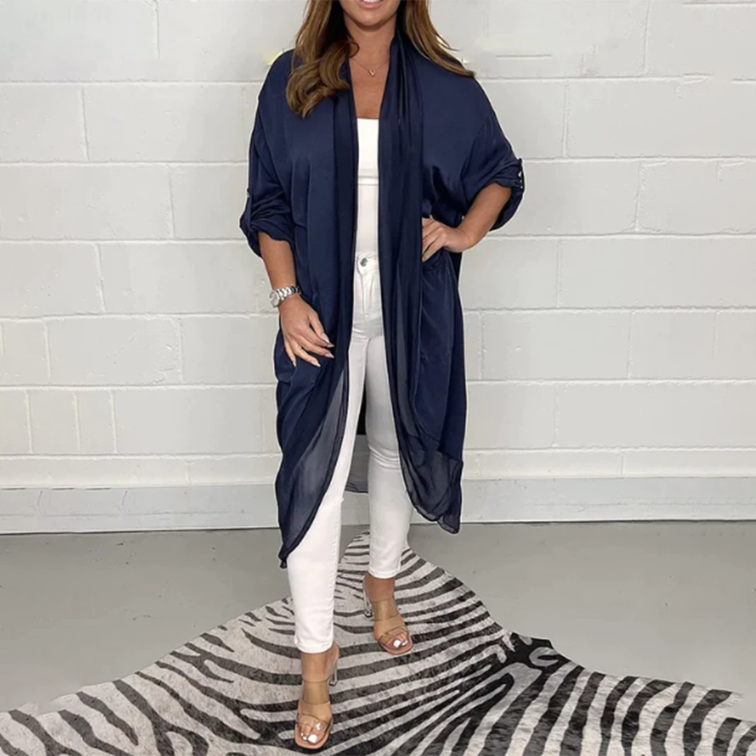 Vrouw in marineblauwe kimono, witte top en broek, op zebraprint tapijt. Modieuze dameskleding, casual chic stijl, trendy outfit.