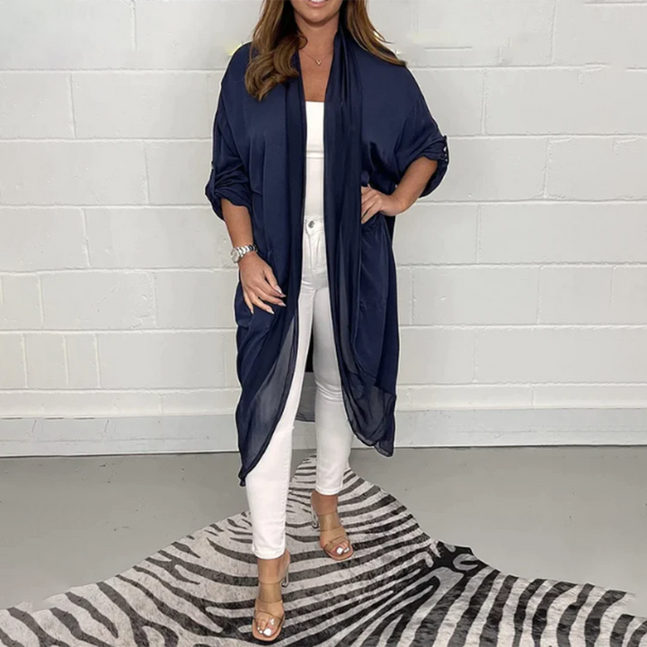 Vrouw in marineblauwe kimono, witte top en broek, op zebraprint tapijt. Modieuze dameskleding, casual chic stijl, trendy outfit.