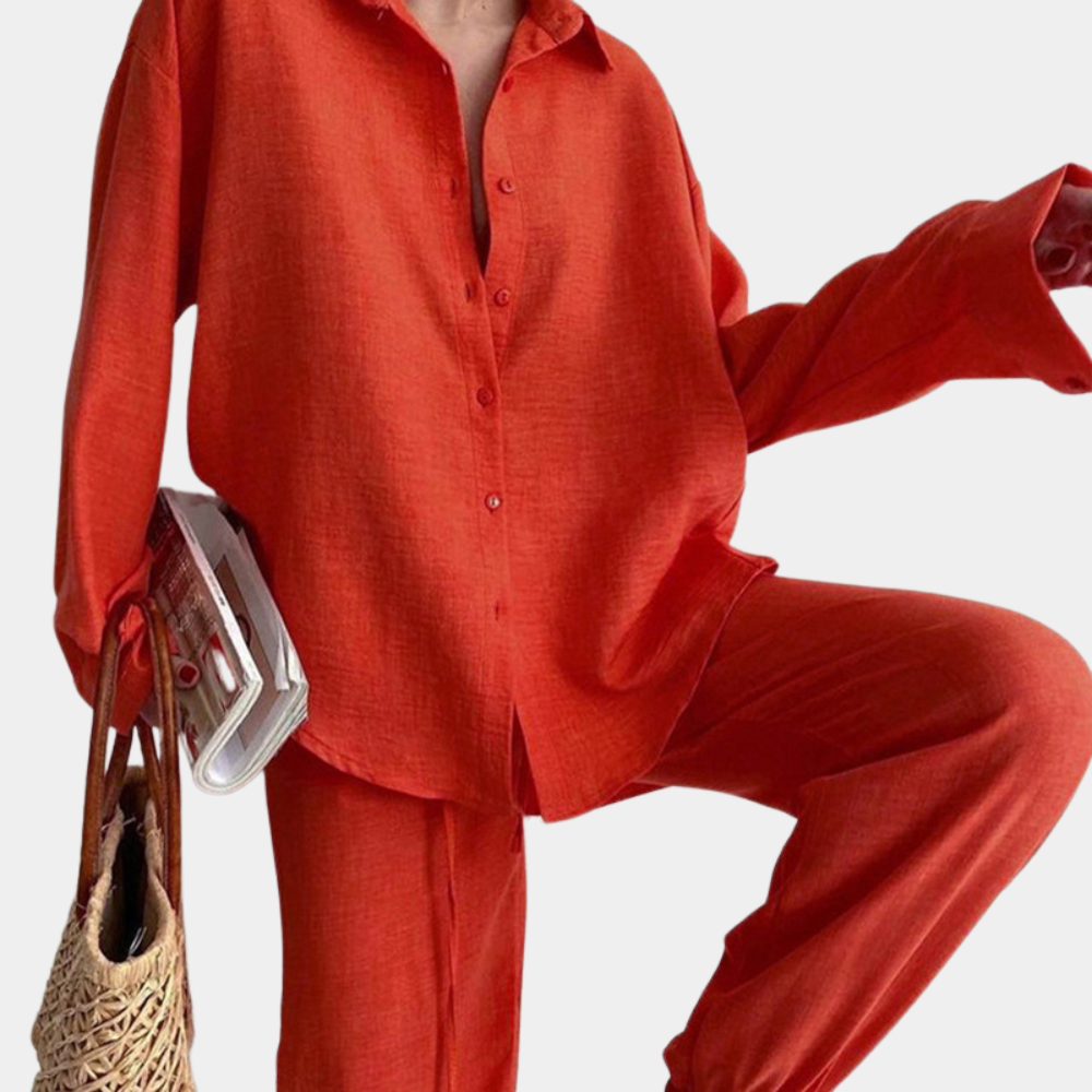 Vrouw in rood linnen damespak met blouse en broek, houdt tijdschrift en rieten tas vast. Modieuze dameskleding, casual chic stijl.