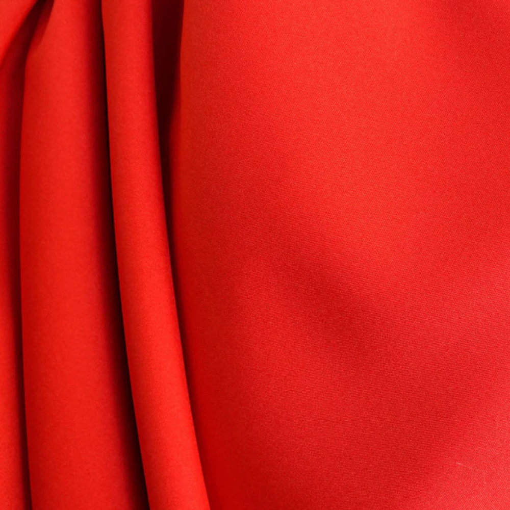 Rode stof close-up, gladde textuur, ideaal voor modeontwerp en interieurdecoratie. Hoogwaardige textielmaterialen, levendige kleur.
