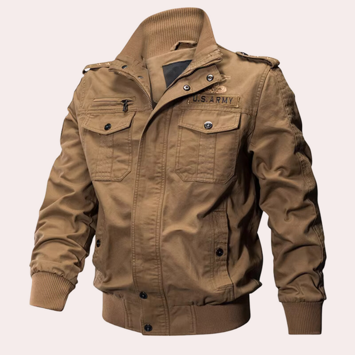 Bruine militaire jas met opstaande kraag, U.S. Army logo, vier zakken en ritssluiting. Stijlvolle herenjas, ideaal voor outdoor en casual gebruik.