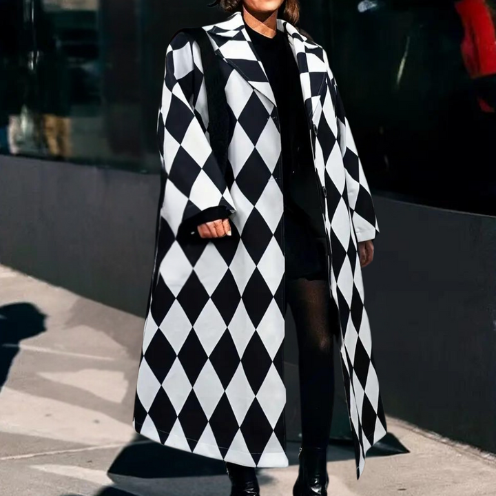 Vrouw in lange zwart-wit geruite jas, modieuze straatstijl, stedelijke achtergrond, trendy wintermode, stijlvolle dameskleding.