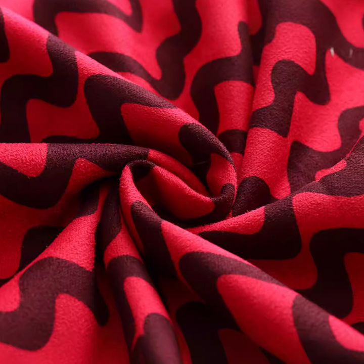 Rode en zwarte stof met golvend patroon, close-up. Ideaal voor modeontwerp, textielproductie en interieurdecoratie. Zachte textuur, levendige kleuren.