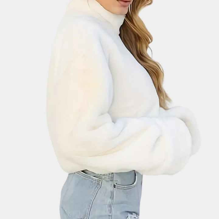 Witte oversized trui met hoge kraag, gedragen door model in lichtblauwe jeans. Modieuze dameskleding, winteroutfit, casual stijl.