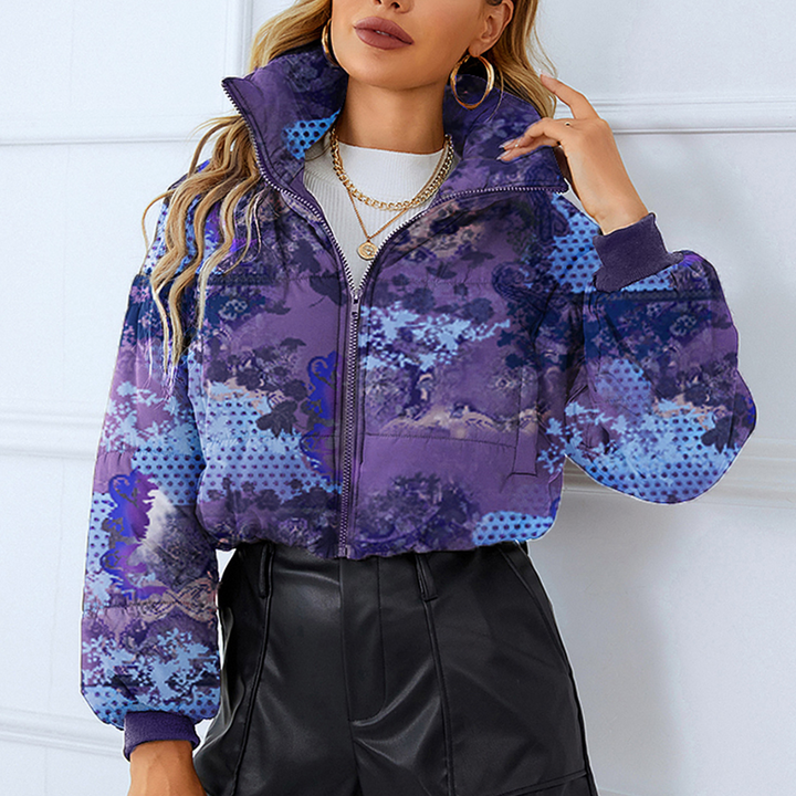 Vrouw draagt stijlvolle paarse en blauwe gewatteerde jas met abstract patroon, gecombineerd met zwarte leren broek. Trendy wintermode, casual outfit.