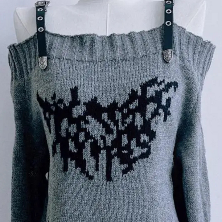 Grijze off-shoulder trui met zwart abstract patroon en leren bandjes, damesmode, trendy winterkleding, stijlvolle gebreide top.