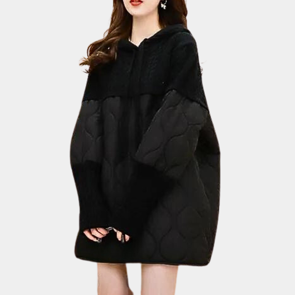 Vrouw in oversized zwarte gewatteerde hoodie, modieuze winterkleding, comfortabele en trendy damesjas, casual streetwear stijl.