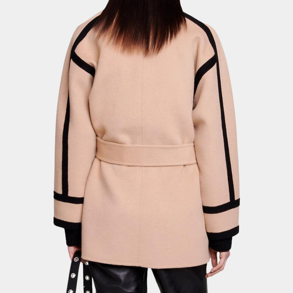 Beige damesjas met zwarte accenten, riem en lange mouwen, gedragen door model. Modieuze winterjas, stijlvolle dameskleding, achteraanzicht.