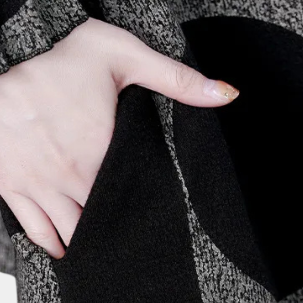Hand in zwarte en grijze wollen jaszak, close-up. Modieuze winterkleding, textuur en detail van de stof. Comfortabele en warme buitenkleding.