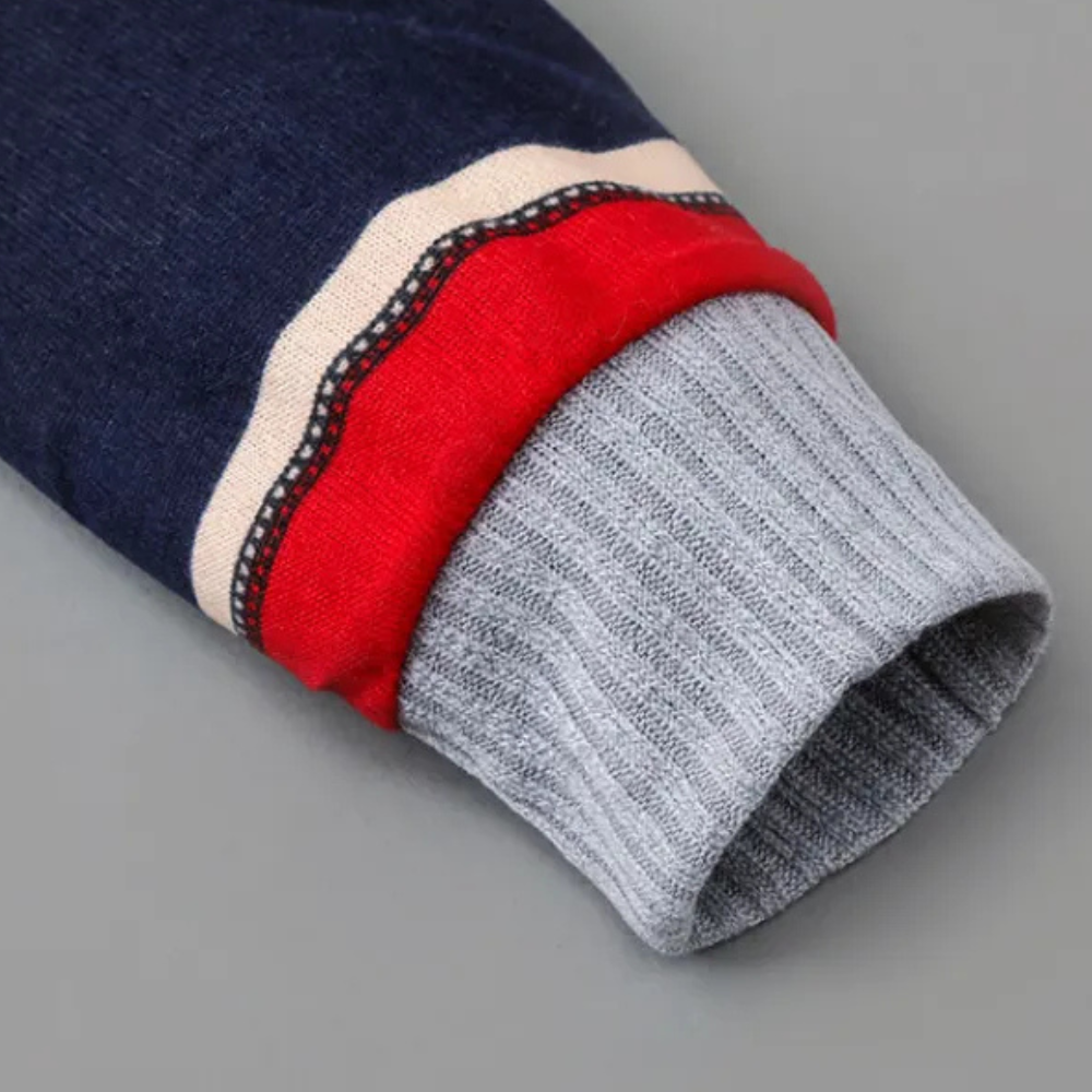 Grijze geribbelde mouwboord van een donkerblauwe trui met rode en witte strepen, modieuze herenkleding, comfortabele wintermode.