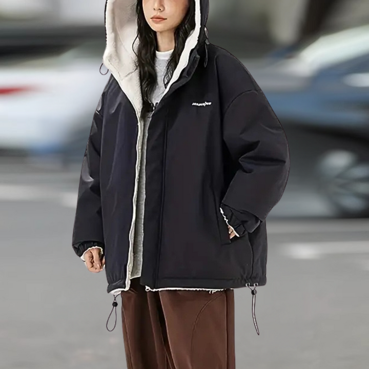 Zwarte oversized winterjas met capuchon, gedragen door een vrouw. Trendy streetwear, warme voering, ideaal voor koude seizoenen.
