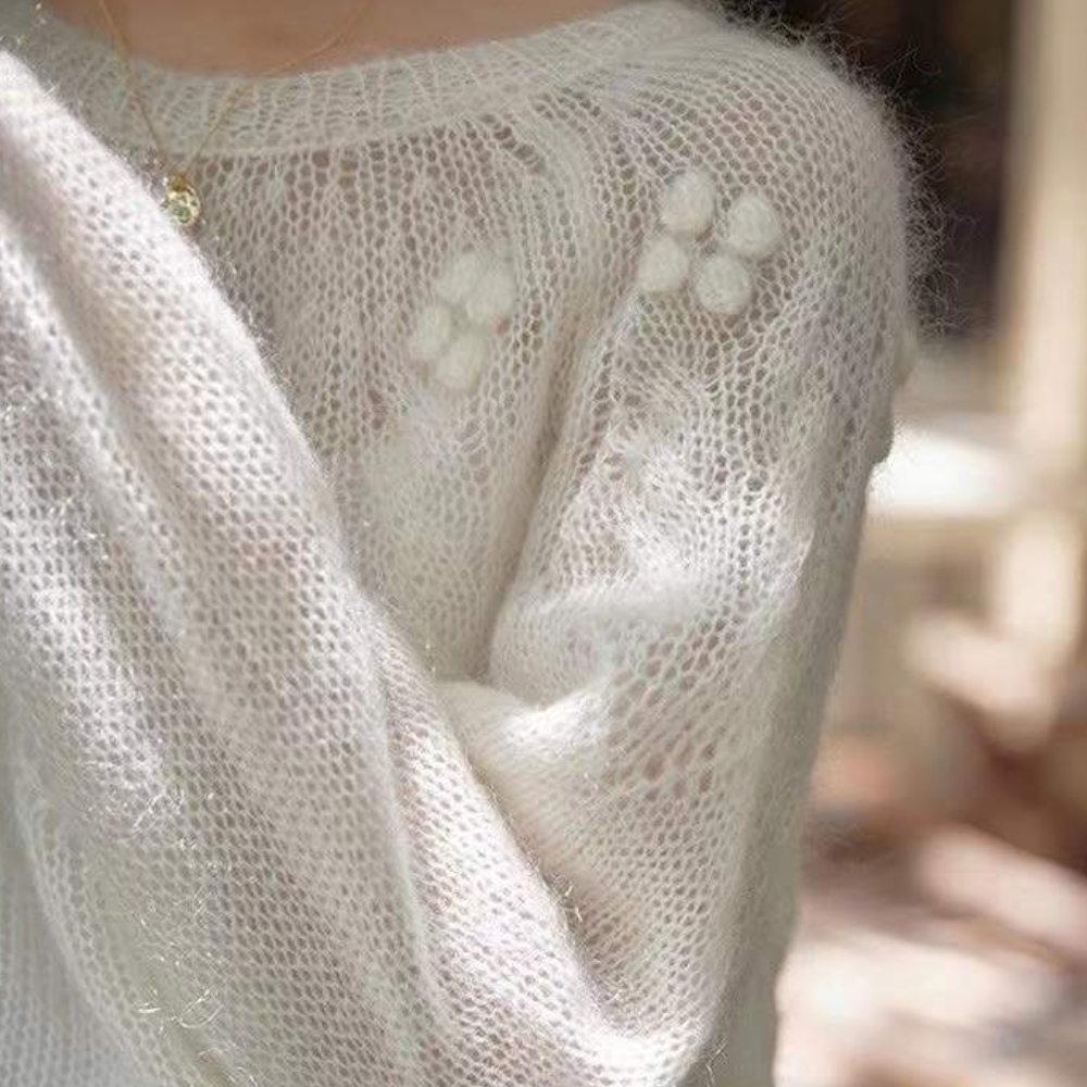 Witte gebreide trui met bloemenpatroon, zachte mohair stof, close-up. Modieuze dameskleding, herfst-winter stijl, comfortabele warme outfit.