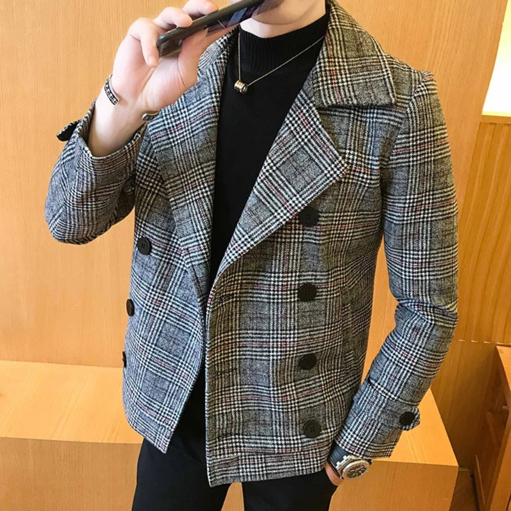 Grijze geruite herenjas met dubbele rij knopen, gedragen door een man in een zwarte trui. Stijlvolle wintermode, casual en elegant design.