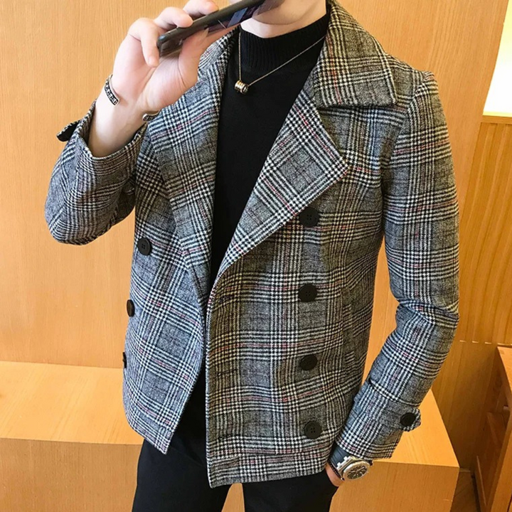 Grijze geruite herenjas met dubbele rij knopen, gedragen door een man in een zwarte trui. Stijlvolle wintermode, casual en elegant design.