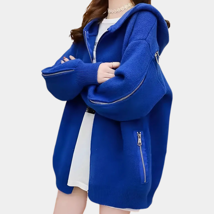 Vrouw in oversized blauwe hoodie met ritsen, witte jurk eronder. Trendy streetwear mode, comfortabele casual stijl.