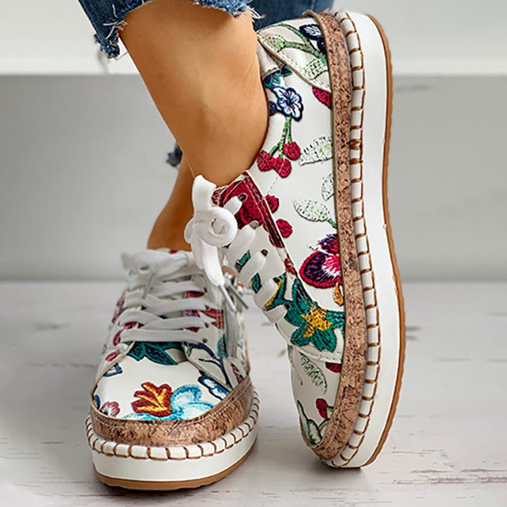 Witte damessneakers met kleurrijke bloemenprint, kurken zool en witte veters. Modieuze casual schoenen voor dames, perfect voor lente en zomer.