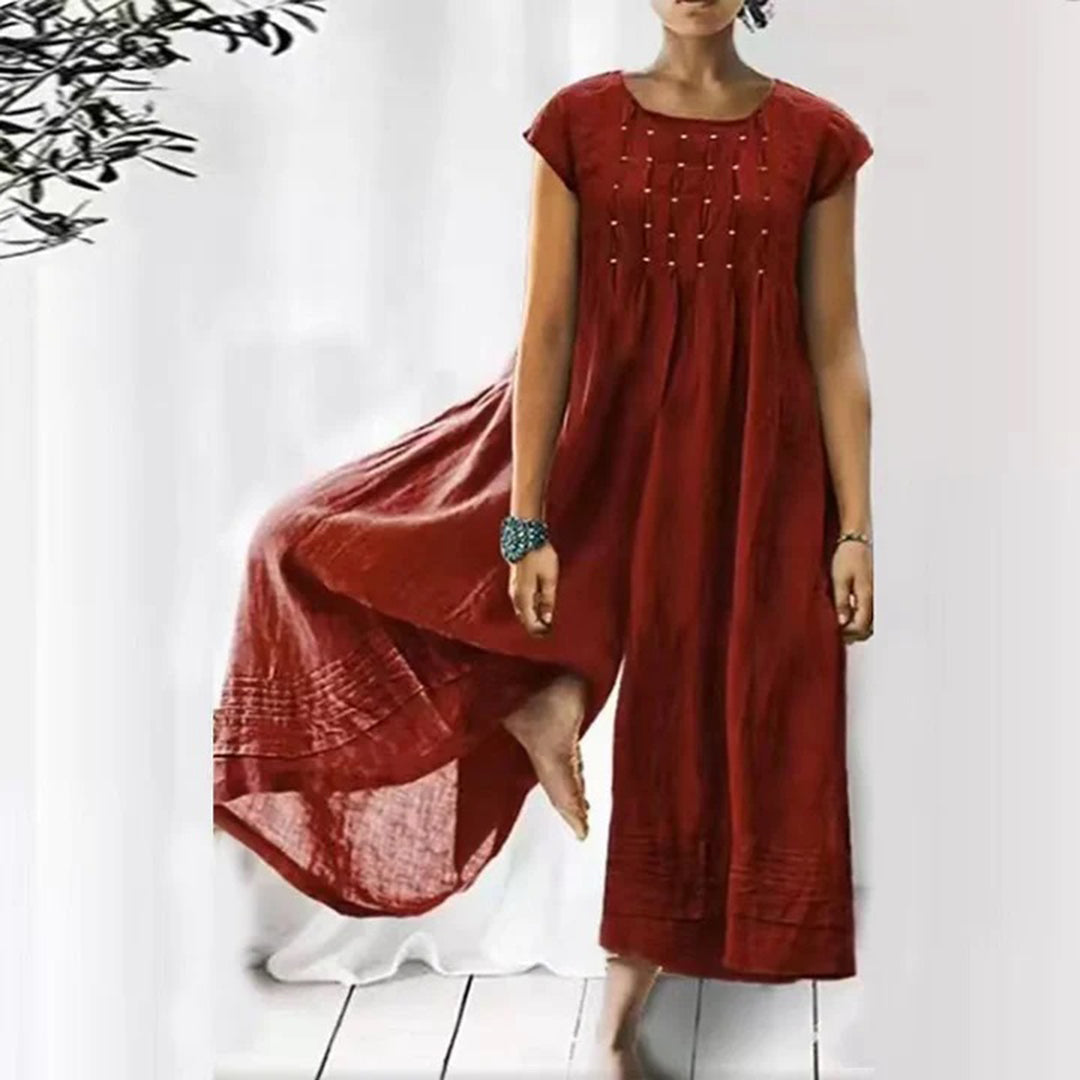 Vrouw in rode, luchtige zomerjurk met korte mouwen en sierlijke plooien, staand op een witte achtergrond. Perfect voor casual en elegante zomermode.