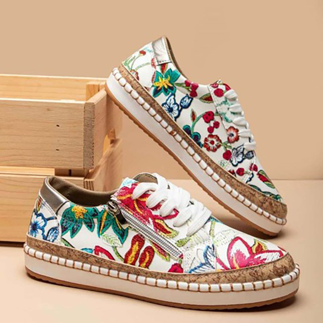 Floral damessneakers met kleurrijk bloemenpatroon, witte veters en rieten zool, casual mode, trendy schoenen, houten achtergrond.