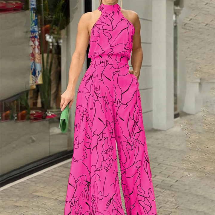 Vrouw in felroze jumpsuit met abstracte zwarte lijnen, staand voor een moderne winkel. Trendy mode, zomeroutfit, opvallende stijl.