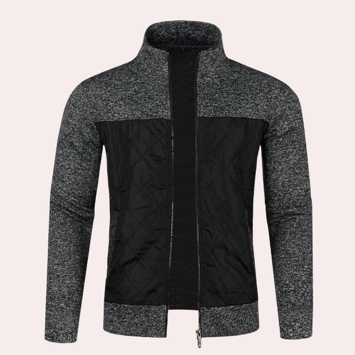 Grijze herenjas met ritssluiting, gebreide mouwen en gewatteerd zwart voorpaneel. Stijlvolle winterjas, ideaal voor casual en formele gelegenheden.