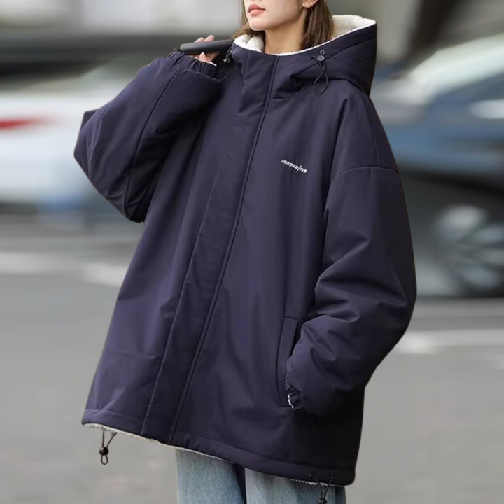 Vrouw in oversized donkerblauwe winterjas met capuchon, casual mode, buitenkleding, trendy streetwear, comfortabele warme jas voor dames.
