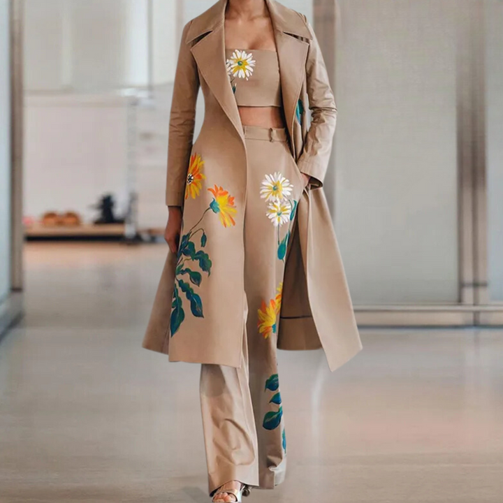 Driedelige damesoutfit met beige trenchcoat, bloemenprint top en broek. Modieuze dameskleding, stijlvolle bloemenpatronen, elegante uitstraling.