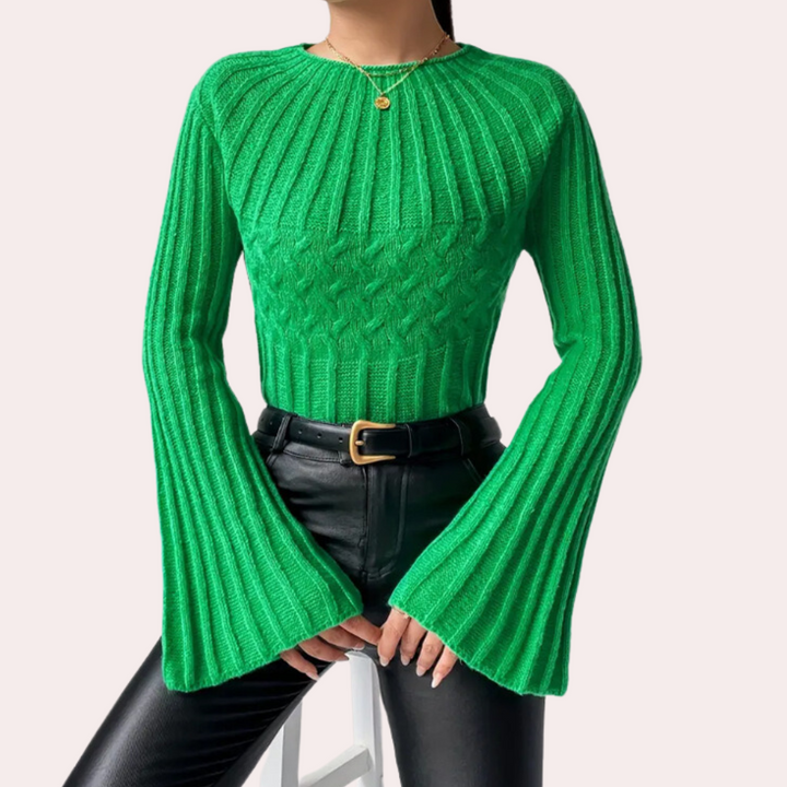 Groene gebreide trui met wijde mouwen, gedragen door model met zwarte leren broek en gouden ketting. Trendy damesmode, herfstkleding.