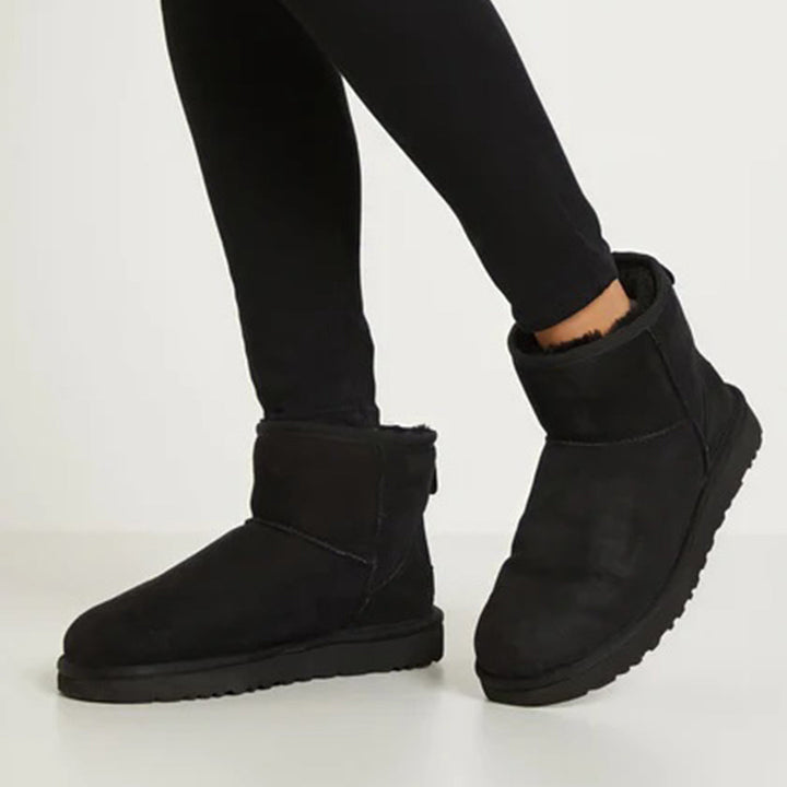 Zwarte winterlaarzen voor dames, gevoerd met bont, gedragen met zwarte legging. Perfect voor koude seizoenen. Comfortabele en stijlvolle schoenen.