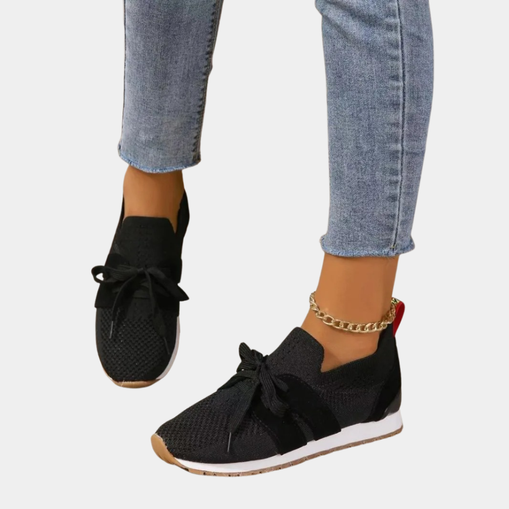 Stijlvolle zwarte damessneakers met veters, gedragen met blauwe jeans. Trendy casual schoenen voor dagelijks gebruik. Perfect voor modebewuste vrouwen.