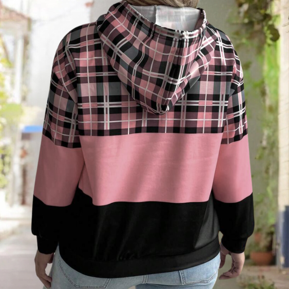 Roze en zwarte geruite hoodie met capuchon, gedragen door persoon buiten. Modieuze streetwear, casual stijl, comfortabele pasvorm.