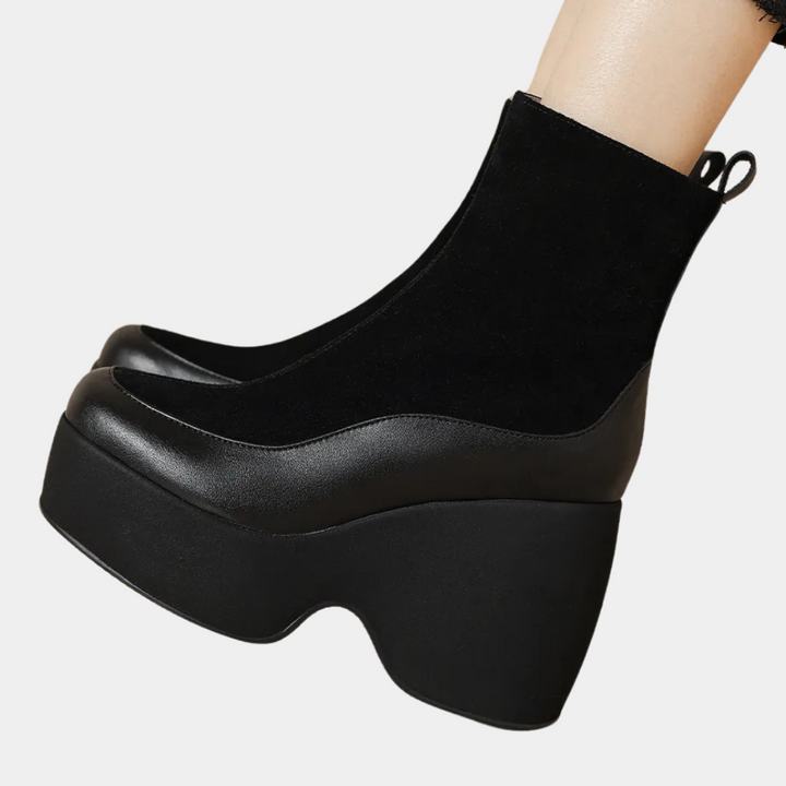 Zwarte platformlaarzen met dikke zool, gemaakt van suède en leer, zijaanzicht. Trendy damesmode, comfortabele hoge hakken.