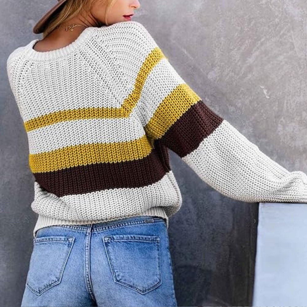 Vrouw in gebreide trui met gele, bruine en witte strepen, gecombineerd met blauwe jeans. Modieuze herfstkleding, casual stijl.