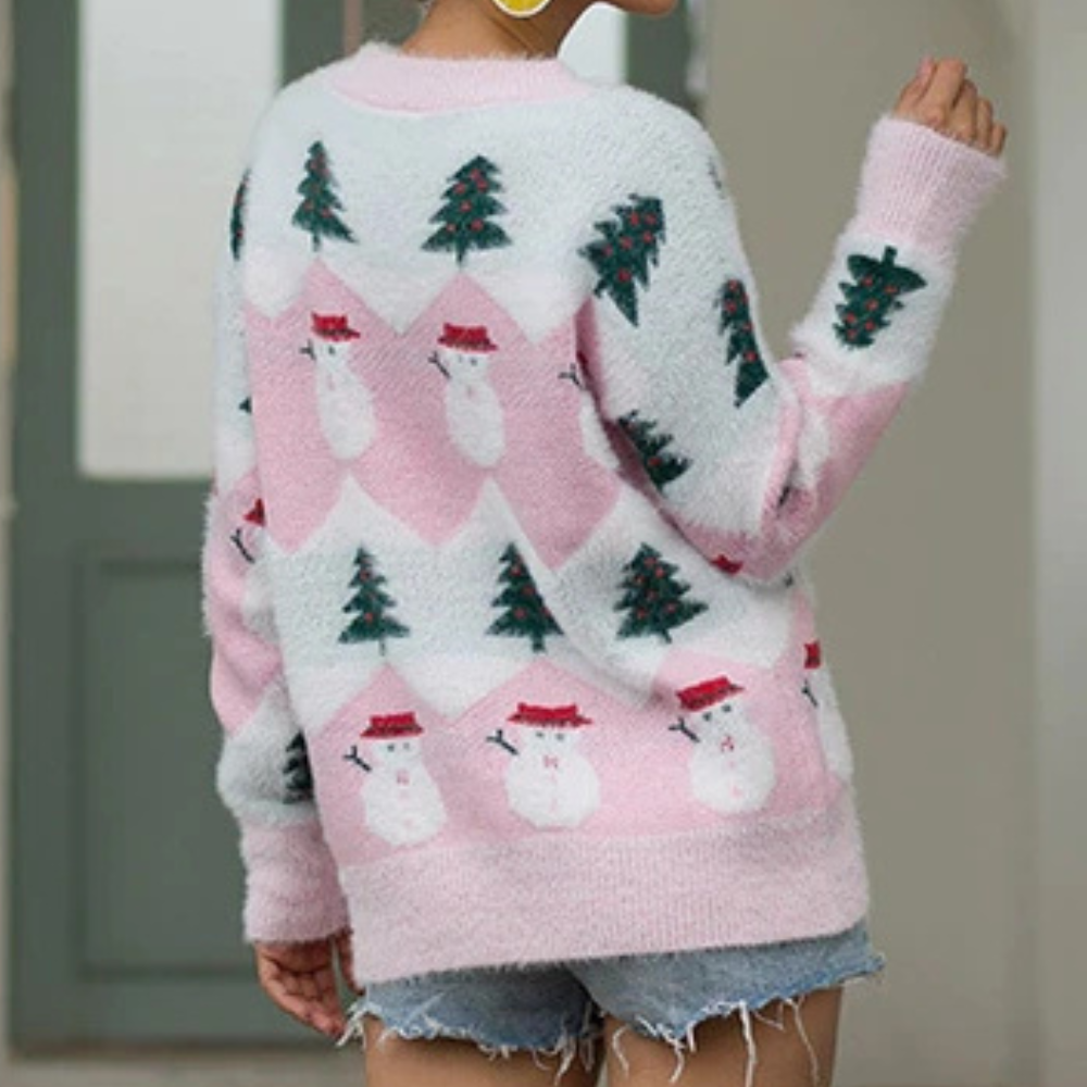 Roze en witte kersttrui met sneeuwpop- en kerstboompatroon, gedragen door een persoon met spijkershort. Perfect voor feestelijke wintermode.