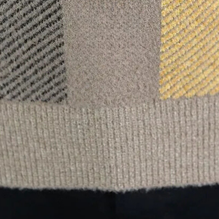 Grijze en gele gebreide trui met geribbelde textuur, close-up. Modieuze herenkleding, wintertrui, warme stoffen, stijlvolle patronen.