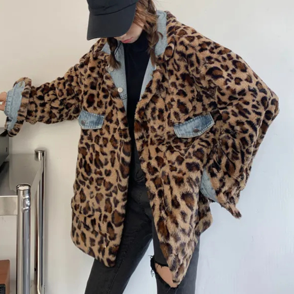 Vrouw in oversized luipaardprint jas met denim details, zwarte pet en gescheurde jeans. Modieuze streetwear outfit, trendy herfstkleding.