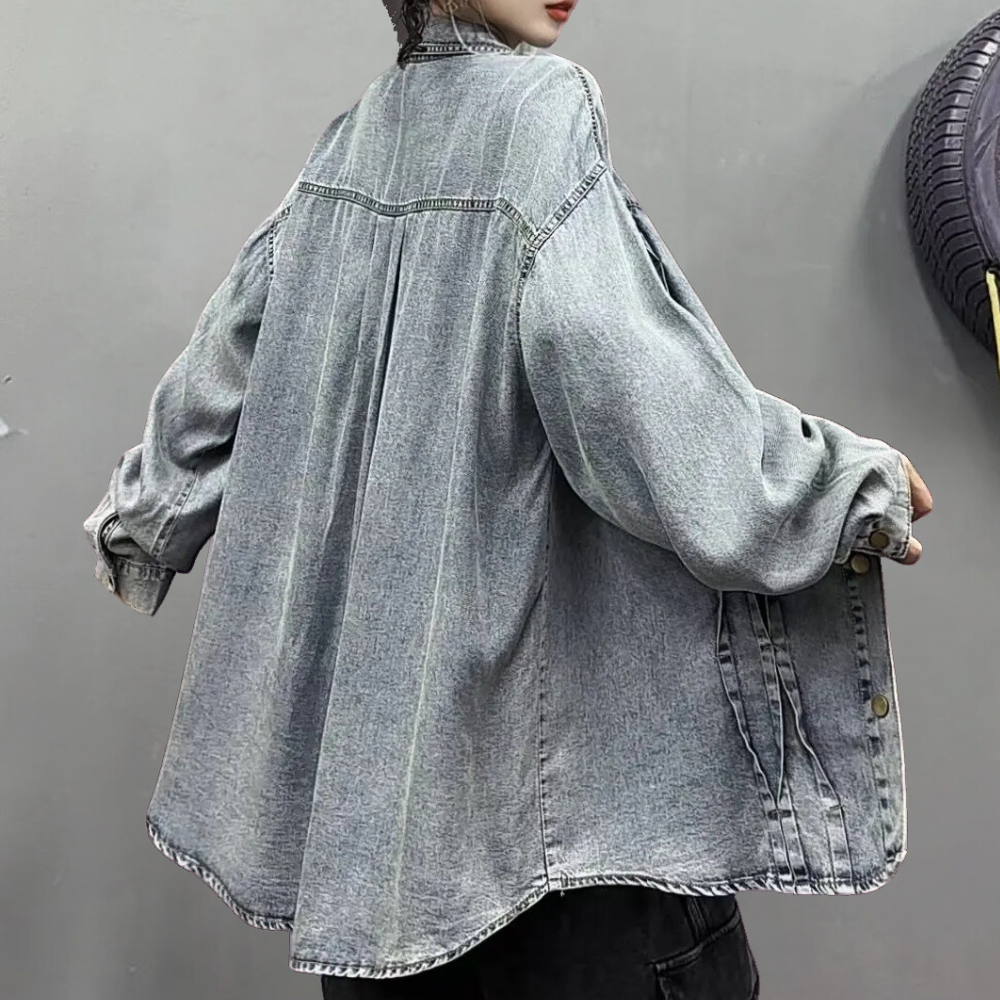Grijze oversized spijkerjas met lange mouwen, casual streetwear stijl, gedragen door persoon tegen neutrale achtergrond. Trendy denim mode.