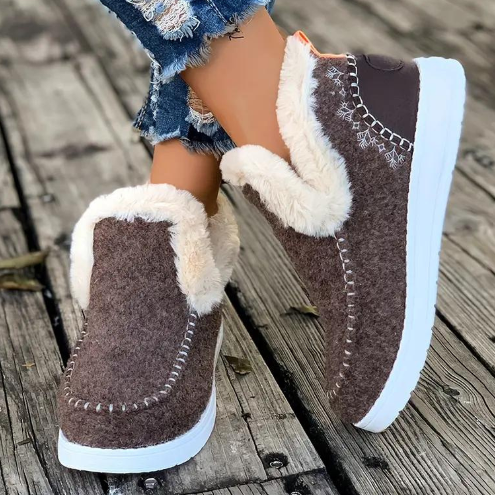 Bruine winterlaarzen met witte zool en warme voering, gedragen op houten vloer. Perfect voor koude dagen. Comfortabele en stijlvolle damesmode.