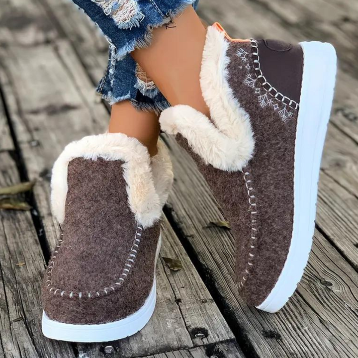 Bruine winterlaarzen met witte zool en warme voering, gedragen op houten vloer. Perfect voor koude dagen. Comfortabele en stijlvolle damesmode.