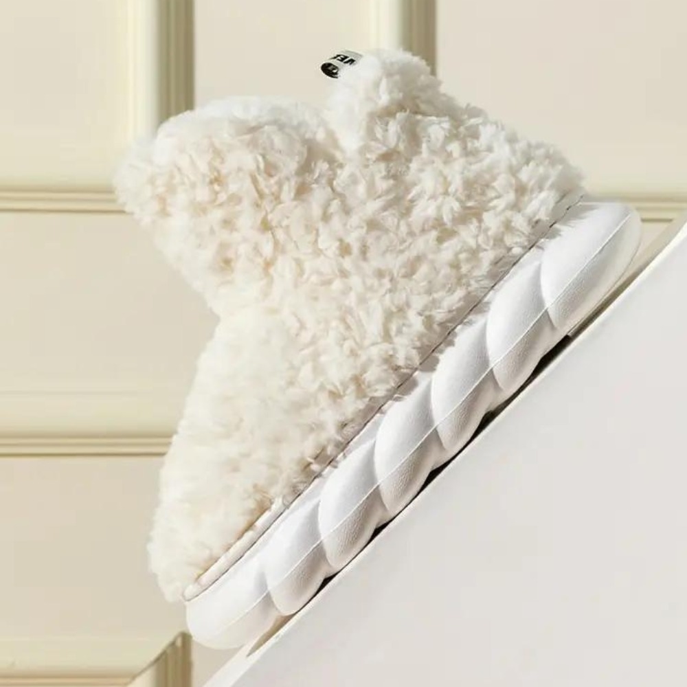 Witte pluche pantoffel met dikke zool, schuin geplaatst tegen beige achtergrond. Comfortabele wintermode, trendy en warm schoeisel.