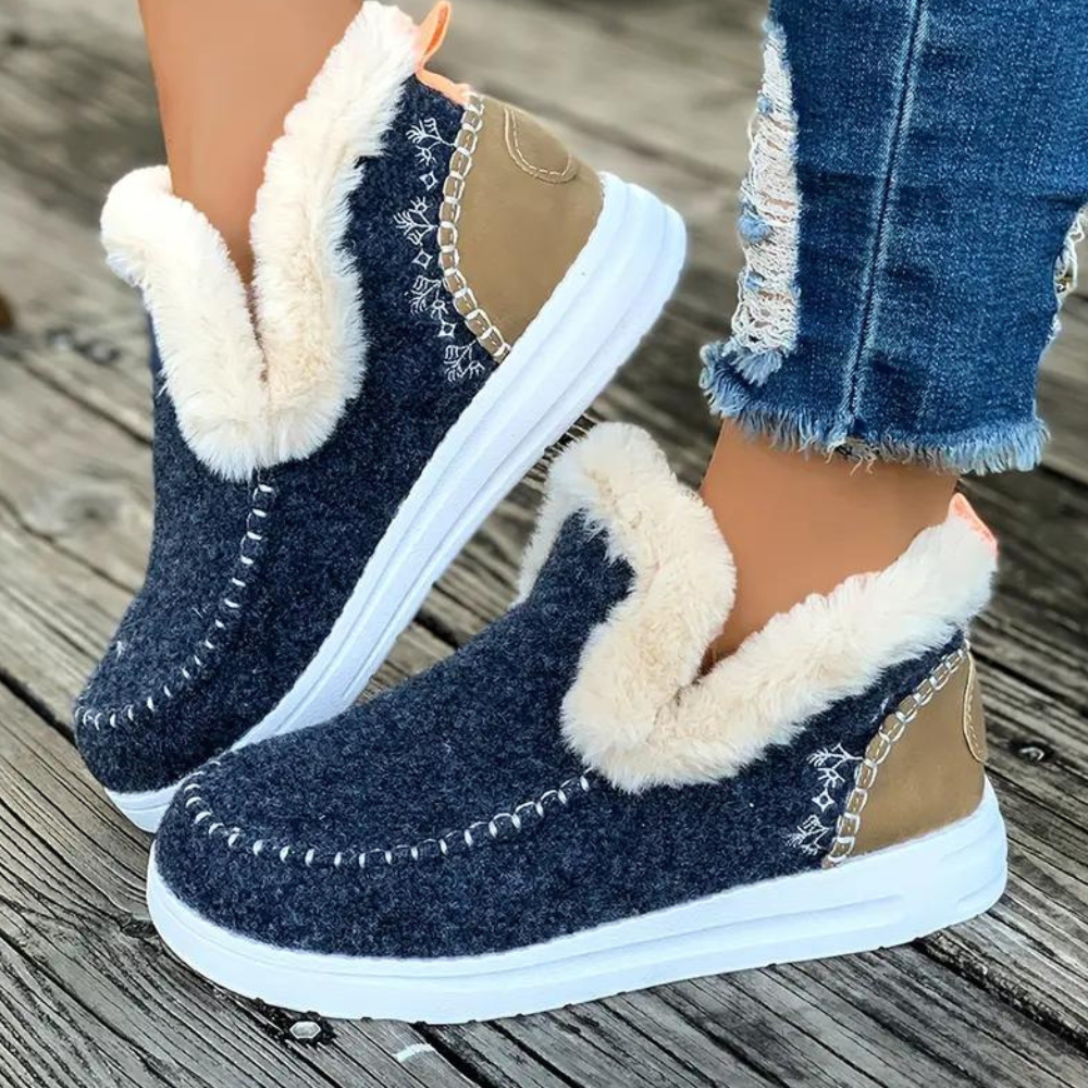 Donkerblauwe winterlaarzen met witte voering, gedragen op houten vloer. Modieuze dameslaarzen, warme voering, casual stijl, perfect voor koude dagen.