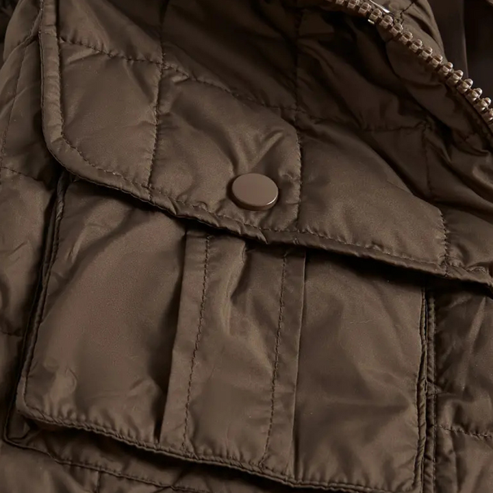 Close-up van een bruine gewatteerde jas met een metalen drukknoop en rits. Ideaal voor wintermode, warme kleding, stijlvolle jas.