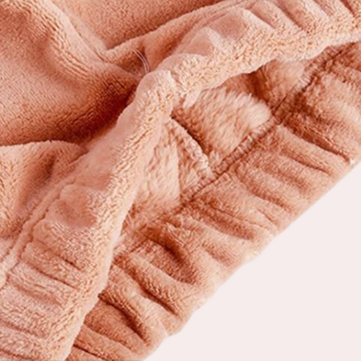Zachte damespyjama van fleece in perzikkleur, close-up van de stoftextuur. Comfortabele nachtkleding, ideaal voor koude nachten.
