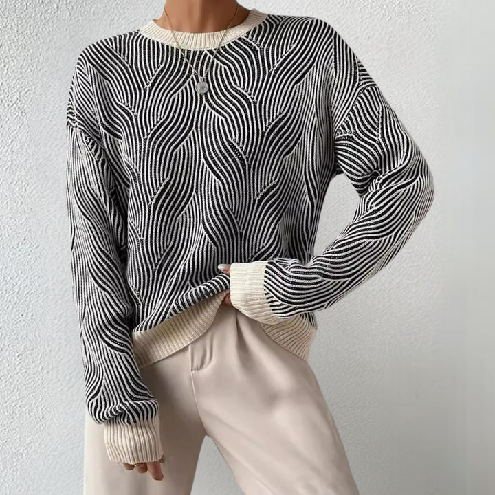 Zwart-witte trui met golvend patroon, lange mouwen en ronde hals, gedragen door model. Modieuze dameskleding, trendy herfst/winter outfit.