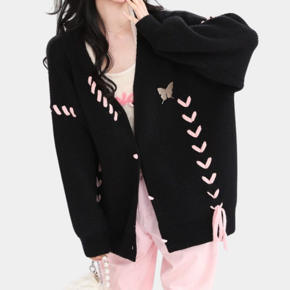 Zwarte gebreide damestrui met roze accenten en vlinderprint, modieuze oversized pasvorm, perfect voor herfst- en winteroutfits.